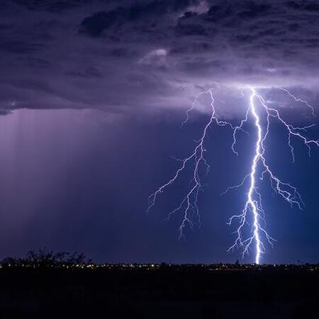 A bright lightning bolt striking down at a city