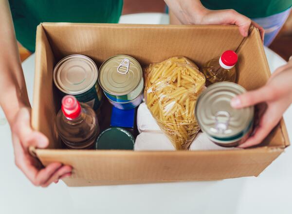 Box filled with cans of food and bags of pasta. 