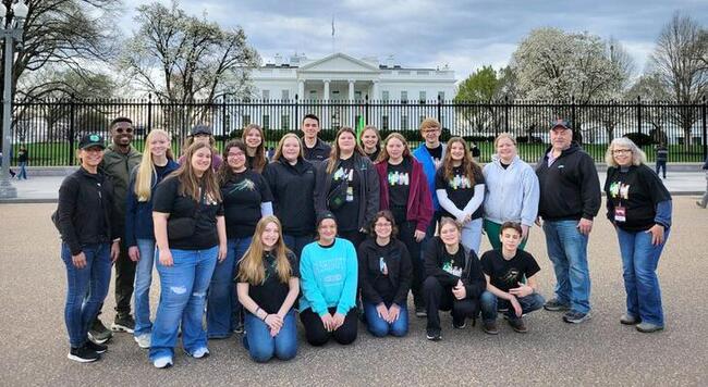 A group of teens pose on the street in front of the White House