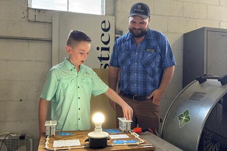 a 4-H member demonstrates his electricity project exhibit to a judge